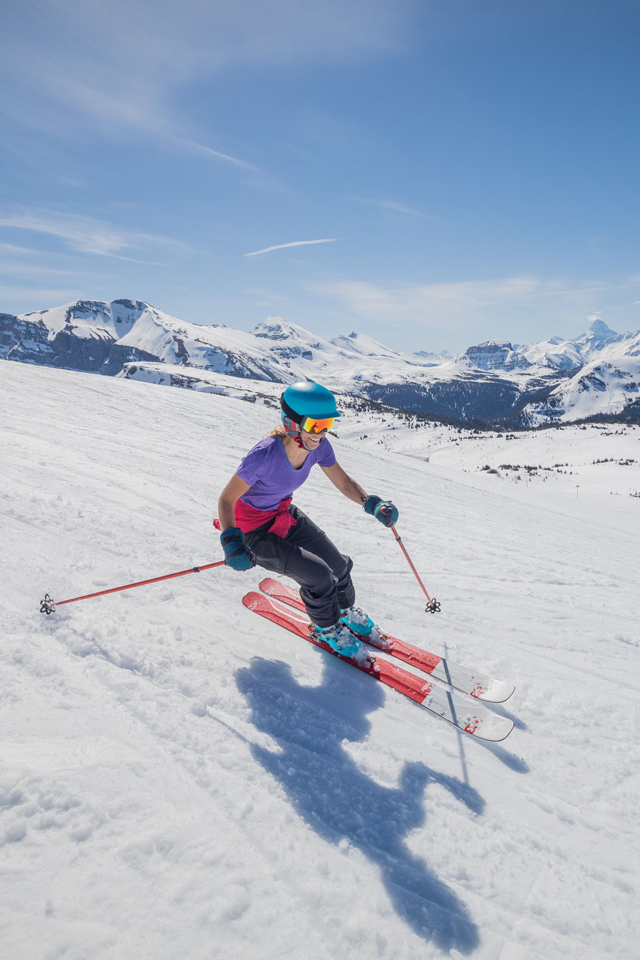 Travel-Alberta--John-Price---Spring-Skiing-WEB woman in otter hotel robe sitting poolside by the fire pits with mountain views in the winter