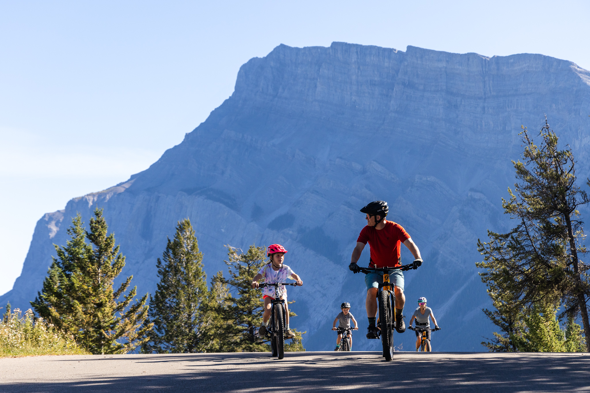 Family riding bikes in front of Mount Rundle