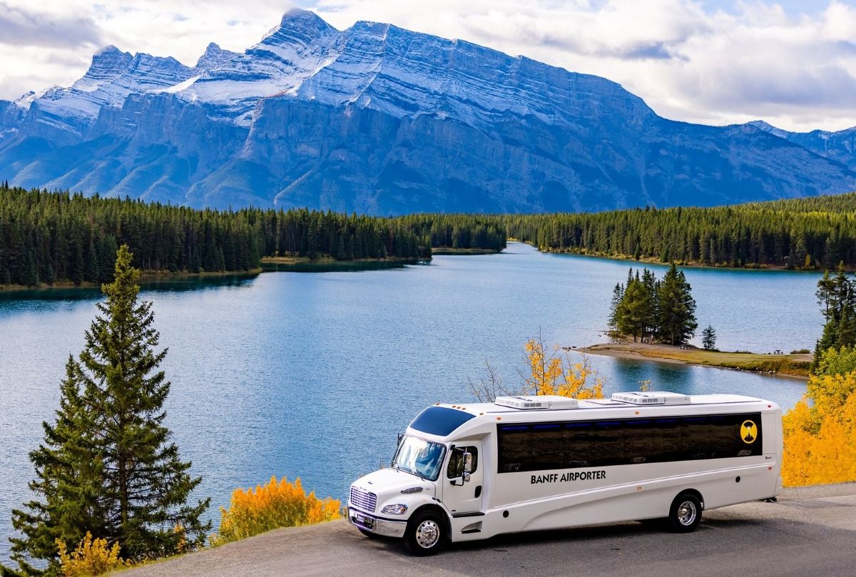 Banff Airporter shuttle bus parked in front of Rundle Mountain in Banff