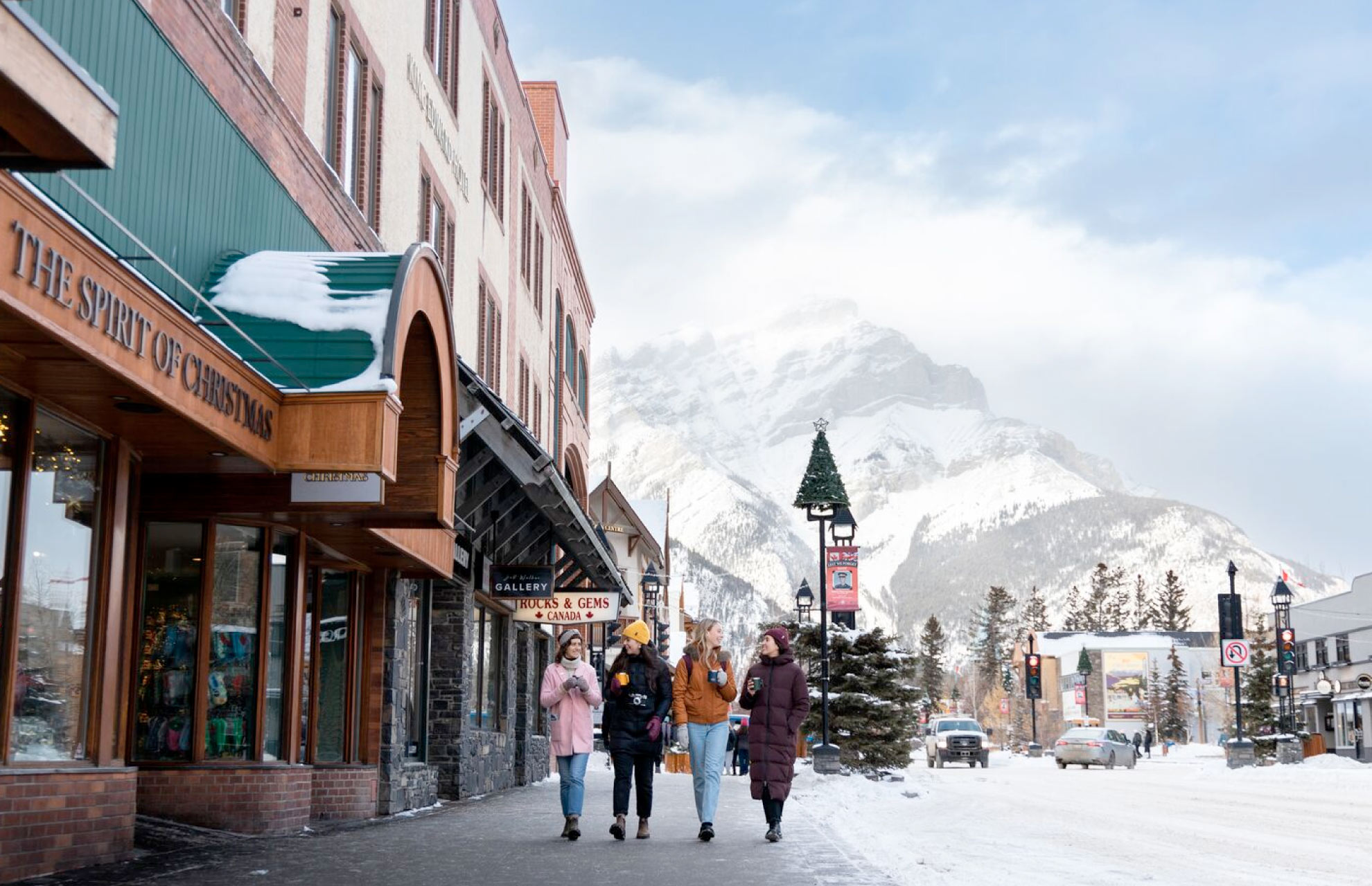 group of women walking down banff avenue in the winter with cascade mountain in the background bluebird skies